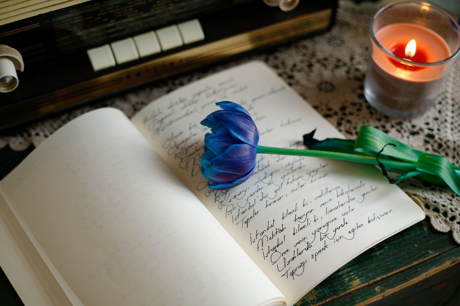 A lit candle beside a journal on a desk representing a small daily ritual