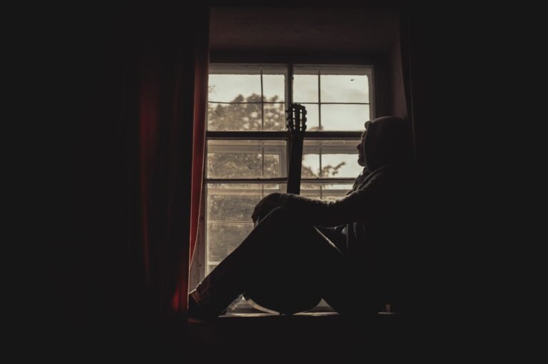 Person sitting alone by a window, reflecting quietly