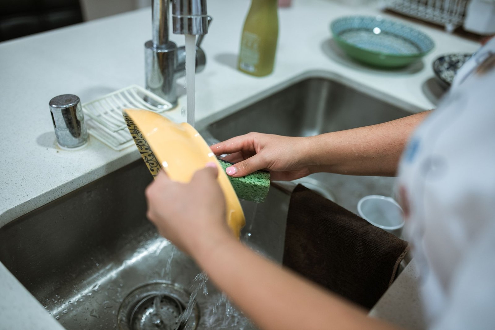 Person mindfully washing dishes in a sunlit kitchen as an everyday ritual
