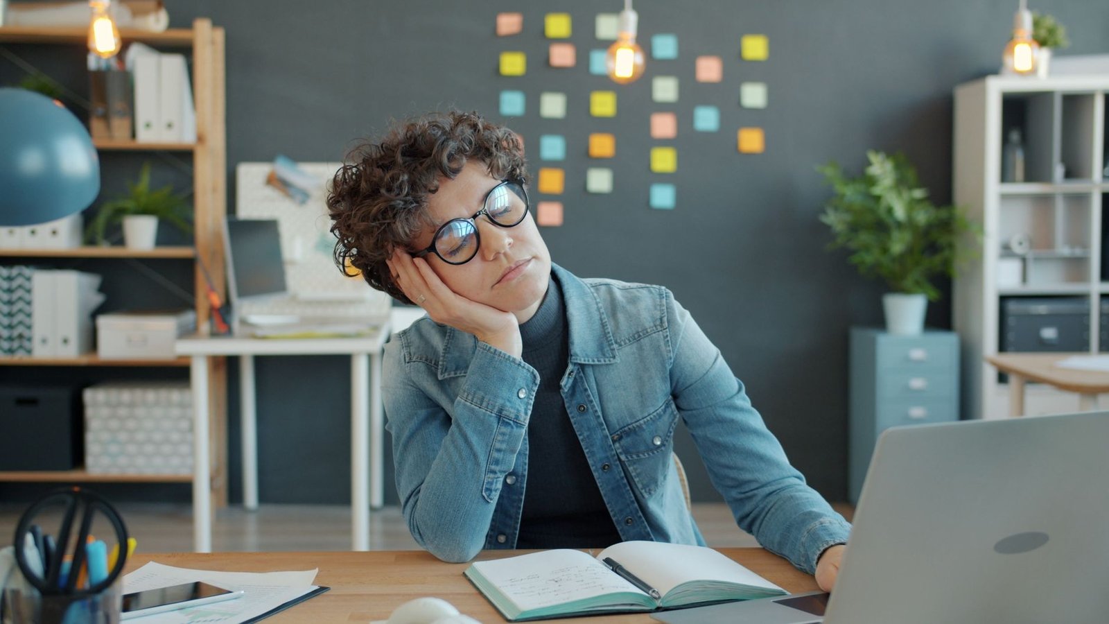 Woman looking fatigued at her desk during the day despite getting enough sleep