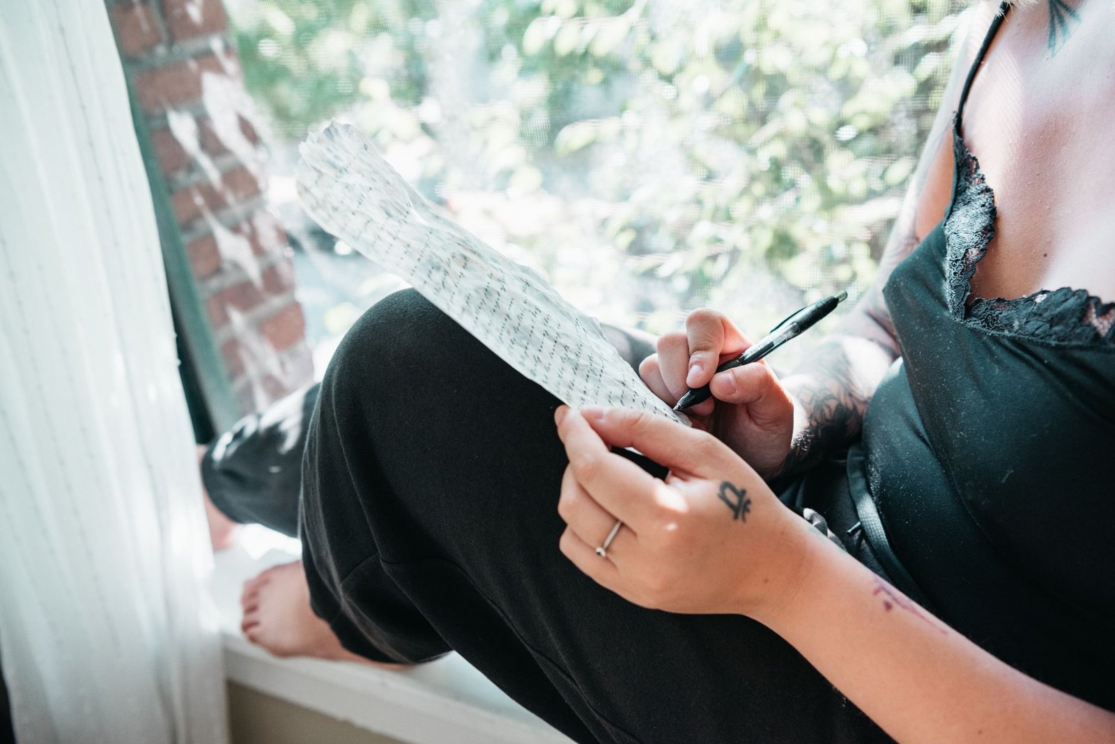 Woman journaling in soft sunlight, reflecting on her personal well-being