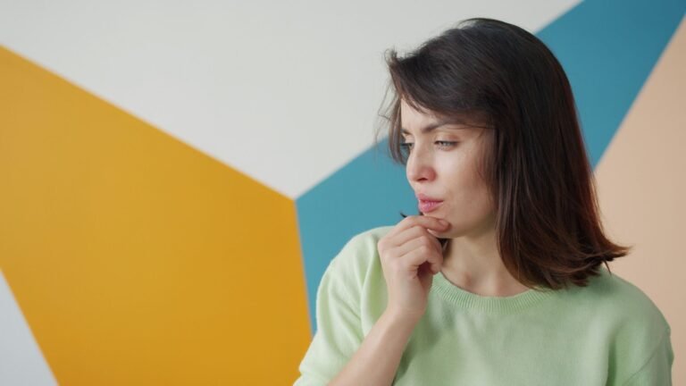 Woman sitting by a window deep in thought, distinguishing overthinking from problem-solving