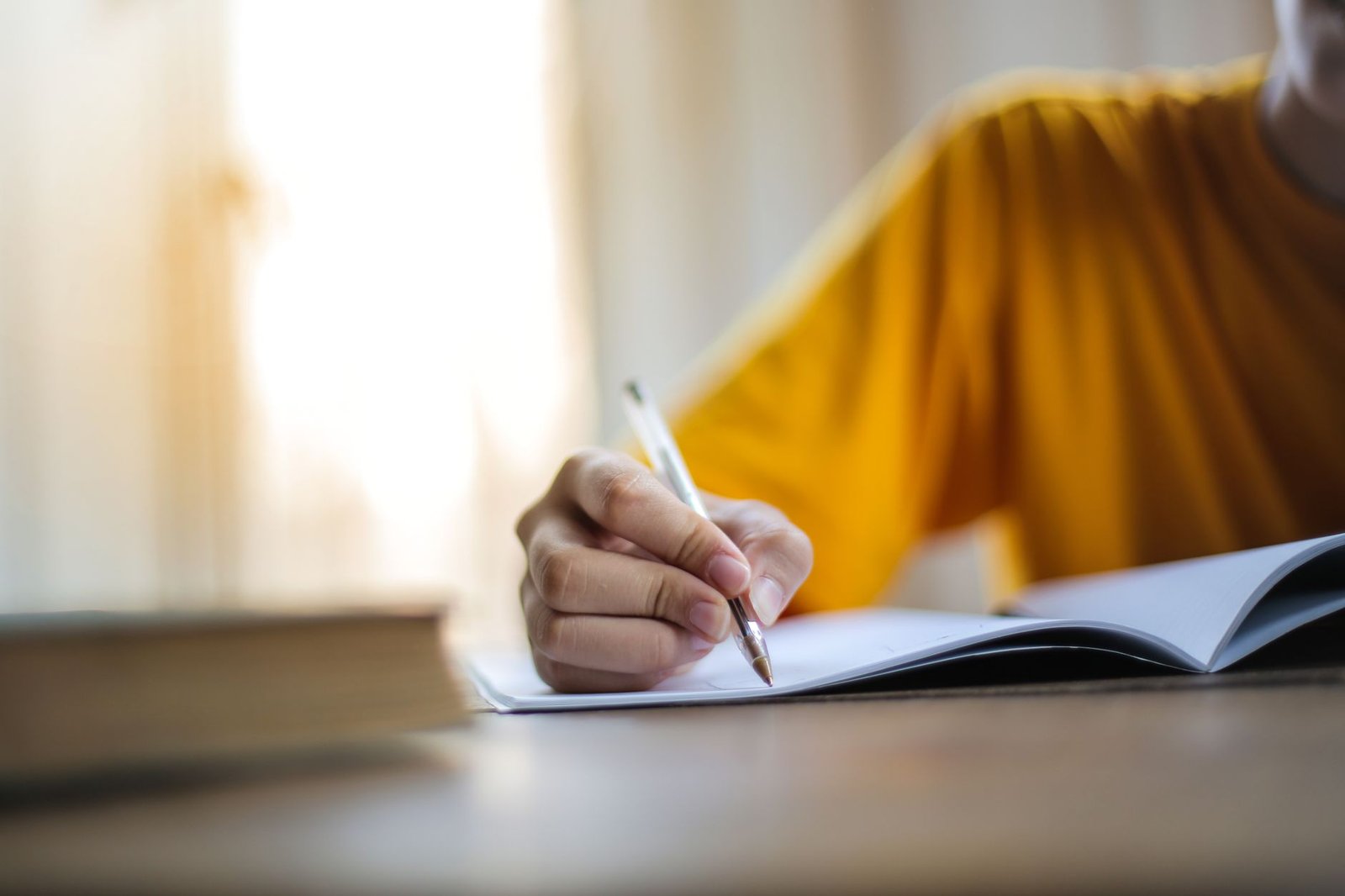 Person writing quietly in a journal near a window