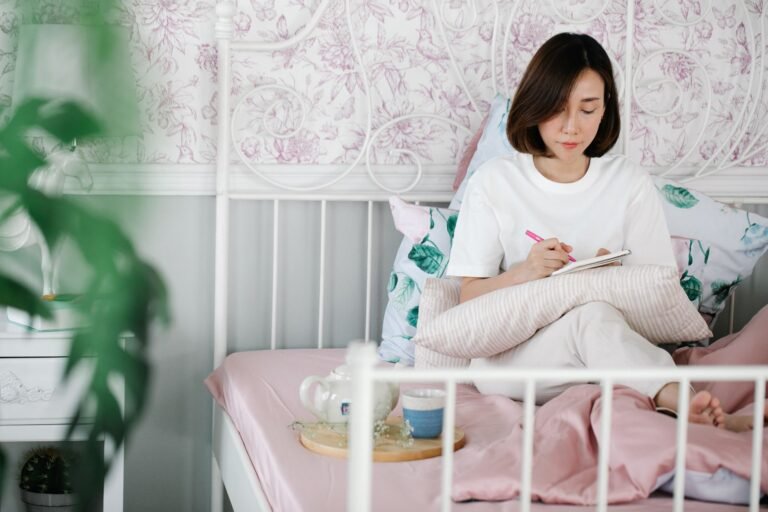 Woman sitting quietly by a window journaling in soft morning light, reflecting on her personal values